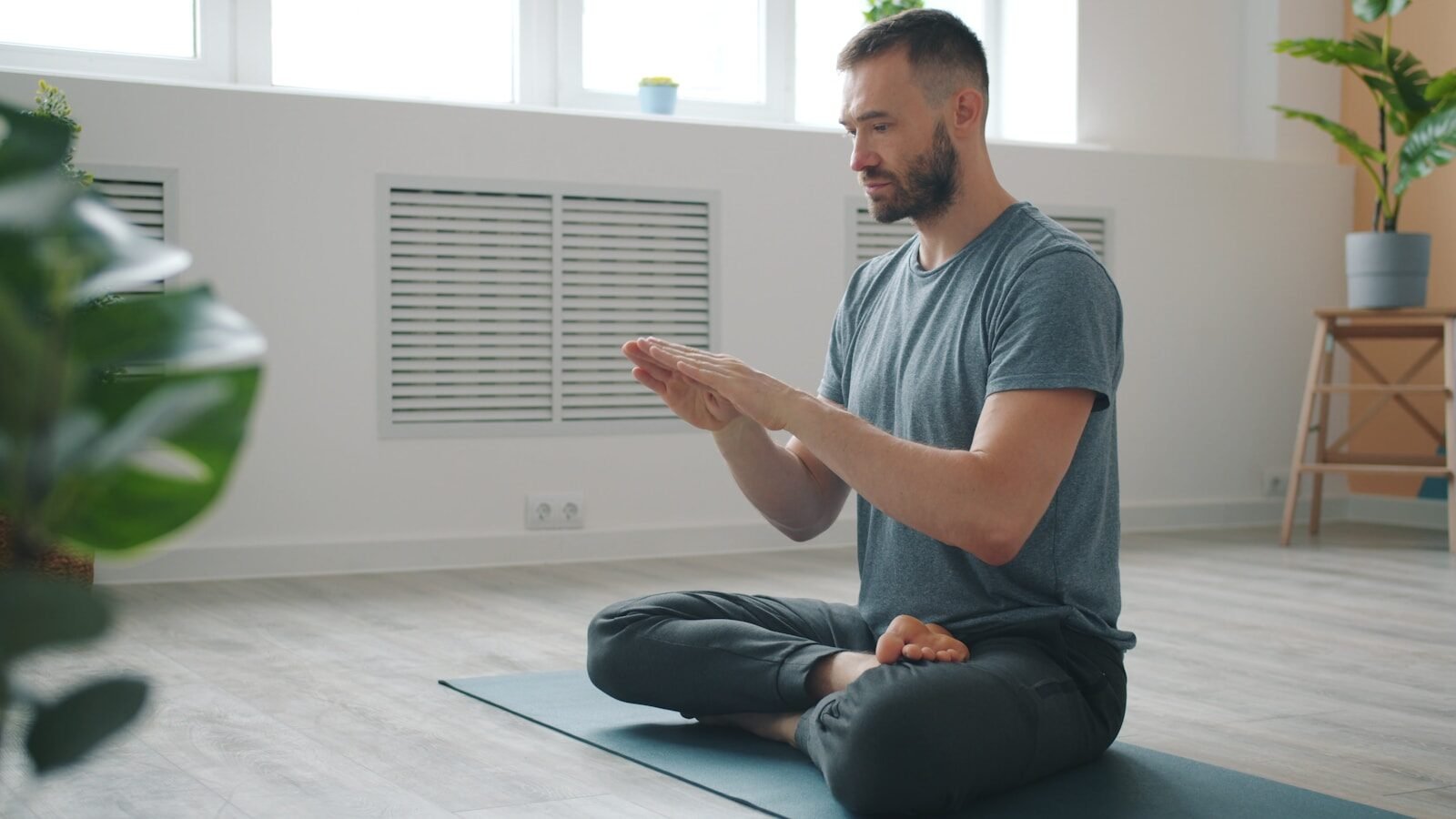 Man meditating in a bright, minimalist room.