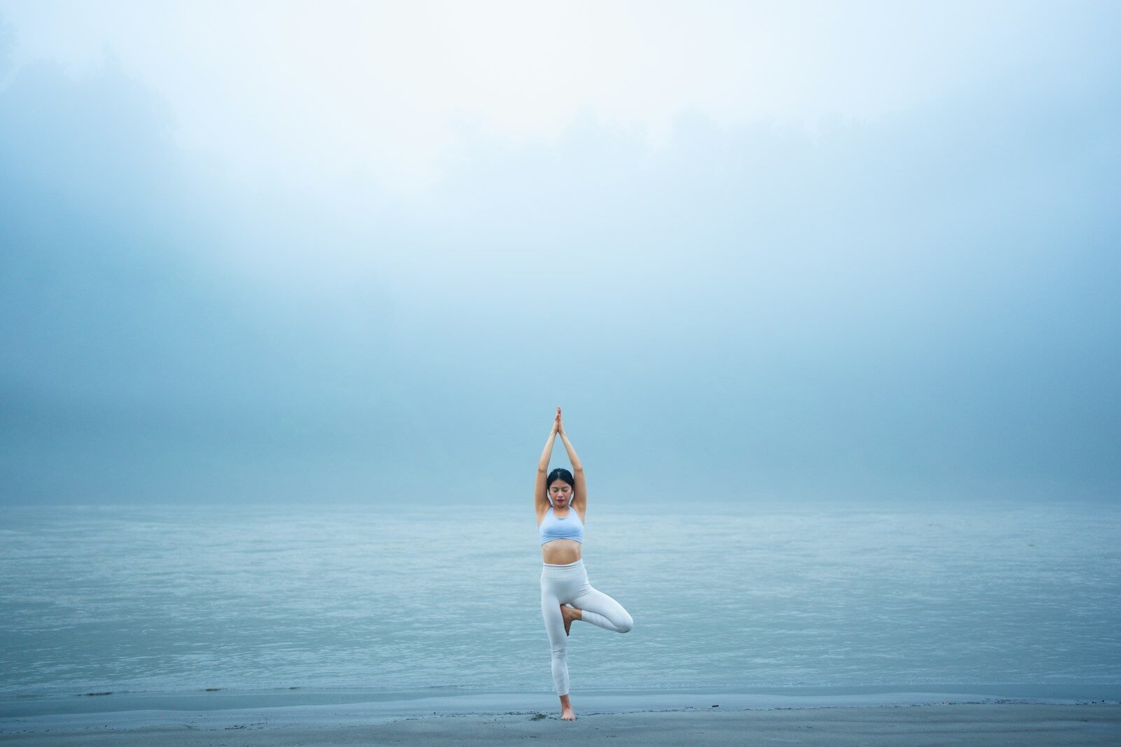A woman standing on one leg on a beach